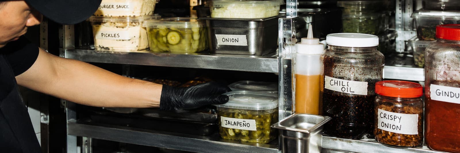 Labelled prep containers of stock on a kitchen shelf